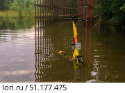 E-scooter and wooden gallery above the bike path in the park, flooded after heavy rain. Редакционное фото, фотограф Евгений Харитонов / Фотобанк Лори