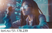 A young girl with glasses engages with holographic displays, showcasing her fascination with technology and innovation at night. Стоковое AI-видео, аниматор Данила Большаков / Фотобанк Лори