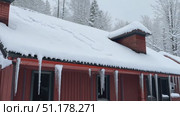 A quiet winter day reveals a snow-laden roof and tranquil surroundings in a beautiful forest blanketed in white. Стоковое AI-видео, аниматор Данила Большаков / Фотобанк Лори
