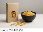 Unbranded pasta packaging with bowl of penne on tabletop. Стоковое AI-изображение, AI-художник Владислав Войтов / Фотобанк Лори