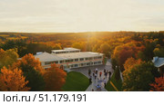 Students enjoy a picturesque autumn evening as the sun sets, illuminating the vibrant fall foliage on campus. Стоковое AI-видео, аниматор Данила Большаков / Фотобанк Лори