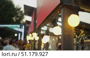 A close-up shot of lanterns, burning with warm yellow light and hanging from a market kiosk at a street food festival. Стоковое видео, видеограф Strunov David / Фотобанк Лори