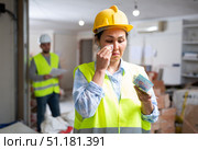 Upset female builder standing in building under renovation with money. Стоковое фото, фотограф Яков Филимонов / Фотобанк Лори