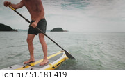 Man paddling on yellow SUP board in calm sea during summer vacation. Concept of active lifestyle, water sport, balance training, and healthy outdoor leisure. Стоковое видео, видеограф Енваев Андрей / Фотобанк Лори