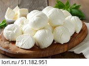 Mozzarella cheese with basil and parmesan on wooden table. Стоковое AI-изображение, AI-художник Katsiaryna Repich / Фотобанк Лори