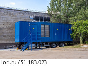 Modern blue diesel powered emergency backup electric generator on portable trailer. Standby backup generator power. Industrial mobile diesel generator for office building, connected to electrical network by cable. Offshore container trailer with powerful electric generator. Стоковое фото, фотограф Данила Большаков / Фотобанк Лори