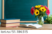 Classroom desk with books and colorful flowers. Стоковое AI-изображение, AI-художник Гузель Набиуллина / Фотобанк Лори
