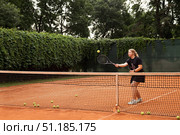Teenage Girl Practicing Tennis Skills on a Clay Court Surrounded by Nature. Стоковое фото, фотограф Aleksandr Golubev / Фотобанк Лори