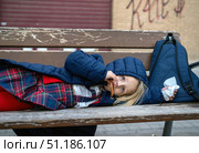 Schoolgirl in uniform resting on bench, munching cookie, relaxing near urban landscape after classes. Стоковое фото, фотограф Данил Руденко / Фотобанк Лори