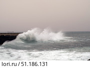 Powerful storm waves slamming wooden pier, massive cargo vessel battling churning sea amid dramatic maritime weather conditions. Стоковое фото, фотограф Данил Руденко / Фотобанк Лори