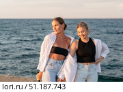 Women Sea Sunset Summer - Two women stand side-by-side on a pier overlooking the ocean at sunset. They wear casual clothing and smile as they enjoy the view. The image evokes a sense of carefree summer fun and connection. Стоковое фото, фотограф svetograph / Фотобанк Лори