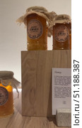 Rows of small, square glass honey jars with twine and decorative tags sit on a wooden surface, bathed in warm light; many more jars are visible,Assorted honey jars and candles are arranged on a table. Редакционное видео, видеограф Zita Khasanova / Фотобанк Лори