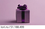 Elegant purple gift box with glossy ribbon placed on a pastel pink background. Minimalist composition ideal for holiday promotions, gift cards, or festive content. Perfect for occasions like Valentine's Day, Women's Day, birthdays, and New Year's. Стоковое AI-видео, аниматор Ксения Чунаева / Фотобанк Лори