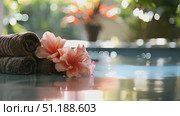 Experience the serene atmosphere of a spa with soft towels and delicate flowers by a peaceful pool, enhancing relaxation and tranquility. Стоковое AI-видео, аниматор Данила Большаков / Фотобанк Лори