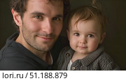 A dad lovingly holds his child, both smiling warmly at one another in a comfortable indoor environment, radiating joy and connection. Стоковое AI-видео, аниматор Данила Большаков / Фотобанк Лори