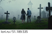 A couple walks together through a foggy cemetery at dusk, surrounded by gravestones and an otherworldly ambiance, evoking blend of romance and mystery. Стоковое AI-видео, аниматор Данила Большаков / Фотобанк Лори