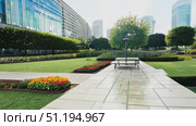 A lush garden invites visitors with vibrant flowers and peaceful pathways amidst a backdrop of modern buildings, showcasing urban tranquility. Стоковое AI-видео, аниматор Данила Большаков / Фотобанк Лори