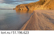Video of beautiful Baikal Lake at sunset light. Olkhon Island. Deserted sandy beach with steep cliffs along shore of Small Sea with blue pure transparent water in August evening. Natural background. Стоковое видео, видеограф Виктория Катьянова / Фотобанк Лори