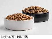 Brown Kibble Pet Food in Two White and Black Bowls. Lot of Dry Granules of Crunchy Dog or Cat Food. Animal Feed Pile. Pet Shop, Delivery. Healthy Treat. Feline Feeding. Domestic Animals Food Banner. Стоковое фото, фотограф Марина Демидюк / Фотобанк Лори