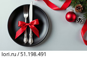 Christmas evening. Festive black plate with silver cutlery on a white background surrounded by Christmas attributes. AI generative. Стоковое AI-изображение, AI-художник Роман Дзюбало / Фотобанк Лори