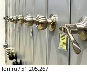A row of silver door knobs are lined up on a shelf.  Russia. Moscow. 24.08.25. Редакционное фото, фотограф Ярославский Максим / Фотобанк Лори