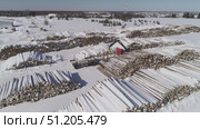 aerial photography of unloading logs from a car trailer using a manipulator and storing logs in an open area in winter. Стоковое видео, видеограф Алексей Сергеев / Фотобанк Лори