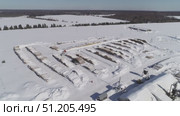 aerial photography of unloading logs from a car trailer using a manipulator and storing logs in an open area in winter. Стоковое видео, видеограф Алексей Сергеев / Фотобанк Лори