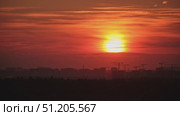 Bright orange sunset over a city skyline with silhouetted construction cranes and buildings in the distance, creating a moody atmosphere, time lapse. Стоковое видео, видеограф Андрей Журавлев / Фотобанк Лори