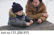 Grandmother swinging a child at the winter park or backyard. Grandma and grandchild sitting on swing. Senior 60s Granny pushing a kid boy on the rope seesaw. Old woman and little boy at the playground. Стоковое видео, видеограф Марина Демидюк / Фотобанк Лори
