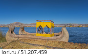 The traditional reed boat Balsa de totora is moored to a man-made island built from reeds. There are cougar heads on the bow. Canopy and deck seats. Clear sky. Copy space. Lake Titicaca. Puno. Peru. Стоковое фото, фотограф Вера Ивановна Кубарева / Фотобанк Лори