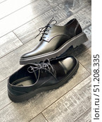 Black leather dress shoes on wooden floor with textured background. Стоковое фото, фотограф Анастасия Золотницкая / Фотобанк Лори