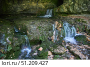 Wild cave outside. The river flows out of the cave, a waterfall. Speleology and surveys. Стоковое фото, фотограф Наталия Кирсанова / Фотобанк Лори