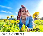 A young woman enjoys a sunny day among vibrant dandelions in a grassy field during early spring. Стоковое фото, фотограф Кривошеина Елена Леонидовна / Фотобанк Лори
