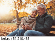 Elderly caucasian couple enjoying autumn outdoors on a park bench. Стоковое AI-изображение, AI-художник Евгения Пархоменко / Фотобанк Лори