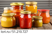 Glass jars filled with spicy pepper sauces on wooden table, background. Стоковое AI-изображение, AI-художник Анастасия Золотницкая / Фотобанк Лори