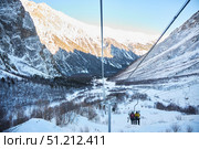 Cei, Russia. - January 06, 2024: A ski lift is visible against the background of a snow-covered mountain. The ski lift is surrounded by trees and snow. Редакционное фото, фотограф Наталия Кирсанова / Фотобанк Лори