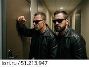 Two Mysterious Figures in Dark Glasses and Leather Jackets Stand Outside a Door, Eagerly Listening and Awaiting the Next Move in a Suspenseful Scenario. Стоковое AI-изображение, AI-художник Башкирова Анна / Фотобанк Лори
