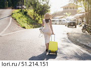 A Young Traveler Carrying a Bright Yellow Suitcase on a Beautiful Scenic Road in a Wonderful Sunny Destination. Стоковое фото, фотограф Владимир Разгуляев / Фотобанк Лори