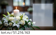 Funeral card template with burning candle and white flowers, condolence background with copy space for obituary text, memorial service announcement with floral arrangement. Стоковое фото, фотограф Павел Муравьев / Фотобанк Лори