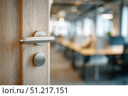 Doorknob. Metal door handle lock and latch of brass on veneer doors. Door wooden half opening through interior office background, selective focus. Modern trends in design. Close-up. Open Space. Стоковое AI-изображение, AI-художник Марина Демидюк / Фотобанк Лори
