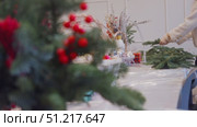 Flower shop is getting ready for Christmas by creating beautiful arrangements and wreaths using spruce branches and festive decorations. Стоковое видео, видеограф Strunov David / Фотобанк Лори
