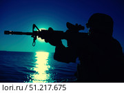 Silhouette of a soldier aiming assault rifle with collimator sight at night. Oleg Zabielin / Stocktrek Images/TASS. Стоковое фото, агентство ТАСС / Фотобанк Лори