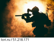 Silhouette of a soldier standing amongst smoke, armed with an assault rifle. Oleg Zabielin / Stocktrek Images/TASS. Стоковое фото, агентство ТАСС / Фотобанк Лори