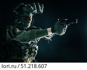 Modern soldier in combat uniform, helmet and radio headset, shooting handgun in the darkness. Oleg Zabielin / Stocktrek Images/TASS. Стоковое фото, агентство ТАСС / Фотобанк Лори