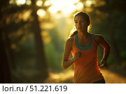 Concentrating on her run, a dedicated sportswoman sprints through a sunlit forest at sunset, embracing the joy of her daily workout amidst the beauty of nature. Стоковое AI-изображение, AI-художник Юрий Поздников / Фотобанк Лори
