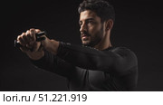 Muscular athlete pulling resistance band across chest, gripping tightly with both hands, displaying powerful fitness movement against dark background. Стоковое AI-видео, аниматор Юрий Поздников / Фотобанк Лори