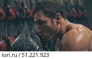 Muscular boxer punching heavy bag, intensely training, sweating profusely while perfecting boxing technique and power. Стоковое AI-видео, аниматор Юрий Поздников / Фотобанк Лори