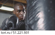 Muscular african american boxer intensely punching heavy bag inside gym, wearing boxing gloves, displaying athletic prowess and powerful striking technique. Стоковое AI-видео, аниматор Юрий Поздников / Фотобанк Лори