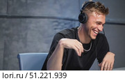 Professional gamer laughing heartily, wearing black t shirt and gaming headset, playing competitive video game in home studio setting. Стоковое AI-видео, аниматор Юрий Поздников / Фотобанк Лори