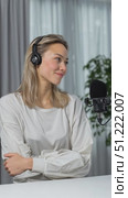 Professional female content creator wearing headphones, speaking confidently into microphone while recording podcast episode for online audience in home studio setting. Стоковое AI-видео, аниматор Юрий Поздников / Фотобанк Лори